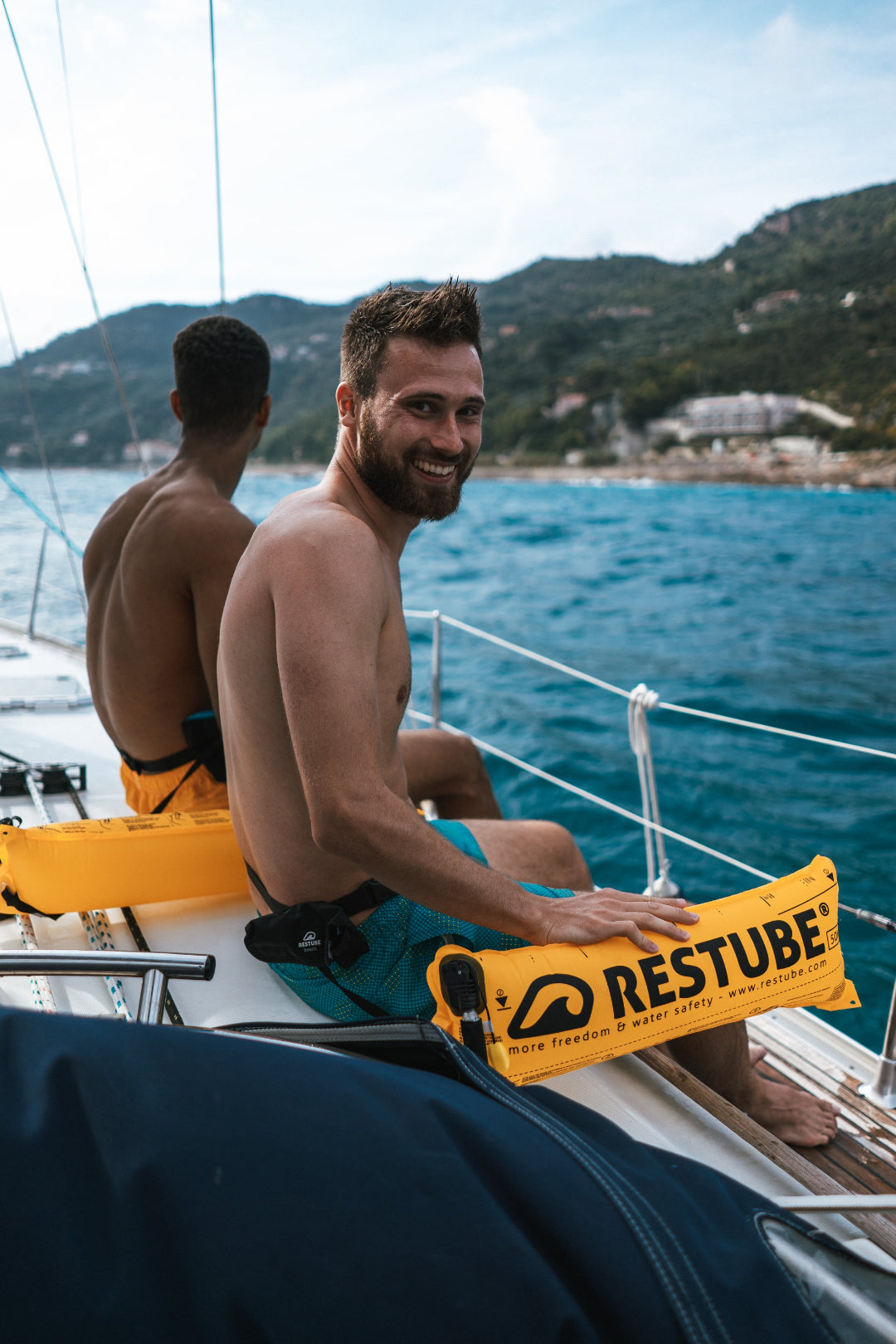 muestra a dos personas con sus boyas Restube en un barco felices. Estas personas estuvieron nadando seguros con sus boyas restube en el mar