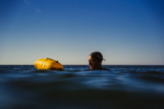 Se muestra a un nadador de aguas abiertas flotando en medio del oceano con su boya de senalizacion RESTUBE PRO, con excelente demarcación de su posición para que otro lo vean sin problema gracias a la boya amarilla RESTUBE