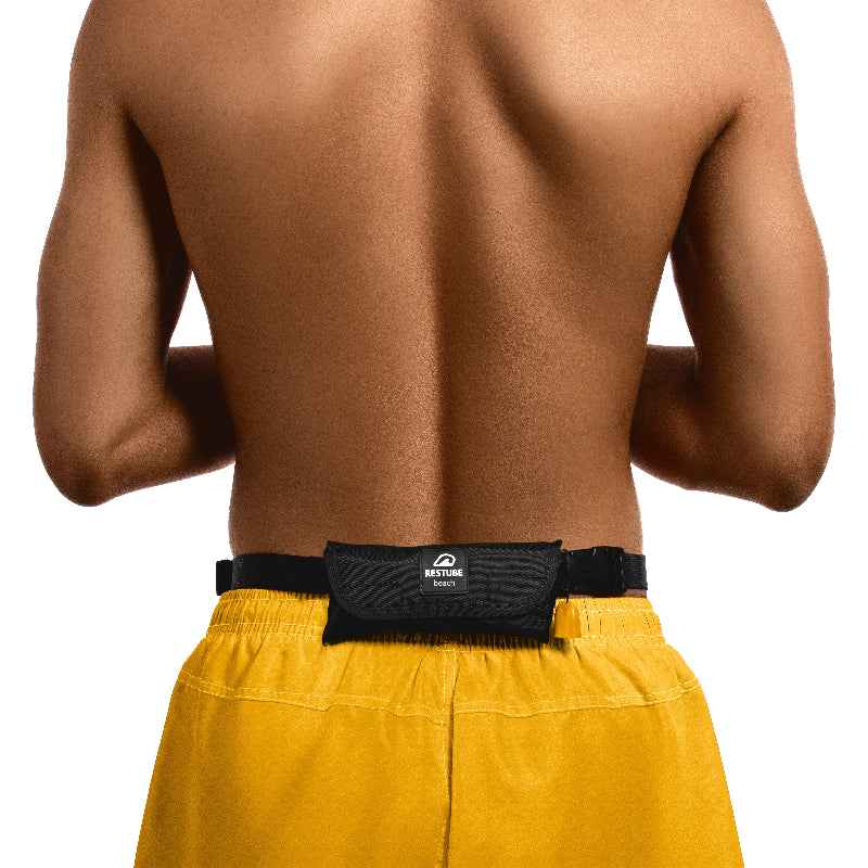 Foto muestra a un hombre con la rinonera Restube Beach puesta en su cintura, sin afectar la movilidad del usuario y sin ser activada la boya, listo para ingresar al agua y contar con flotacion extra