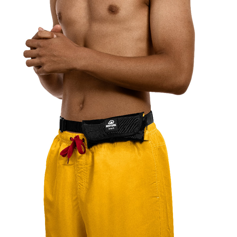 Foto muestra a un hombre con la rinonera Restube Beach puesta en su cintura al lado izquierdo, sin afectar la movilidad del usuario y sin ser activada la boya. listo para ingresar al agua y contar con flotacion extra